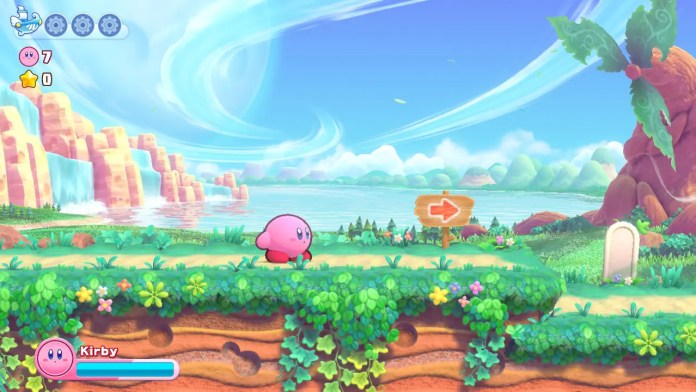 Kirby se tient dans l'un des niveaux de Cookie Country sur un sentier herbeux.  Il y a un ciel bleu clair avec des nuages ​​en arrière-plan.  La scène est de Return to Dream Land.